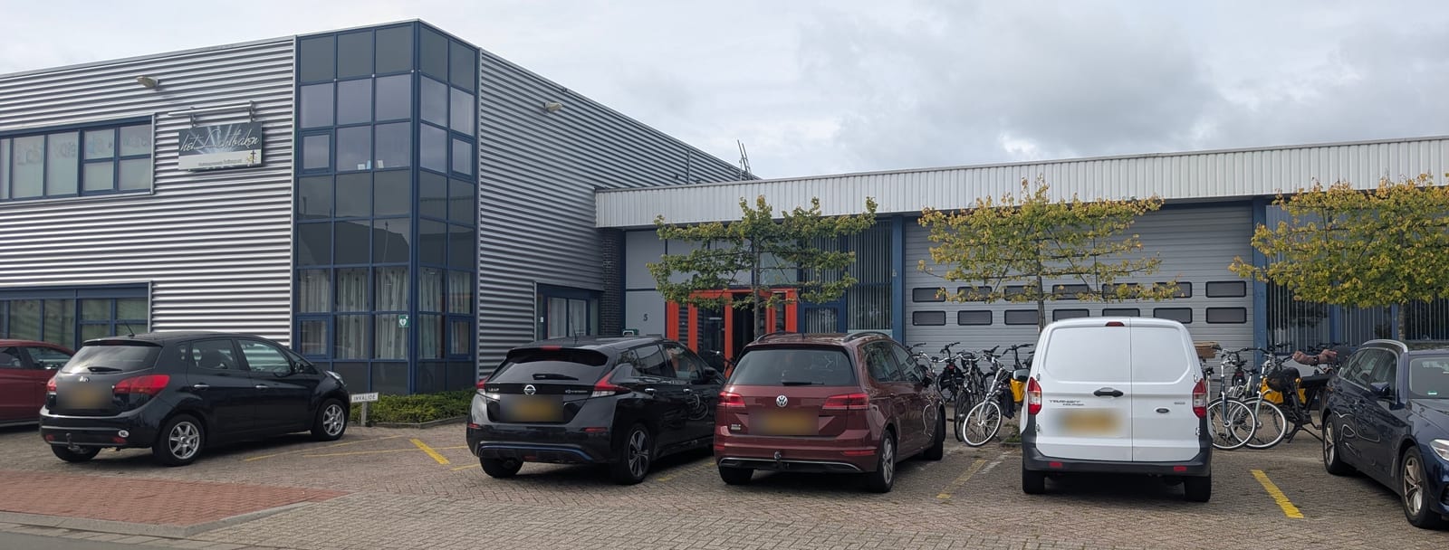 Het Lichtbaken aan de Marconistraat 5, met de oranje deuren van de ingang en de parkeerplaats ervoor